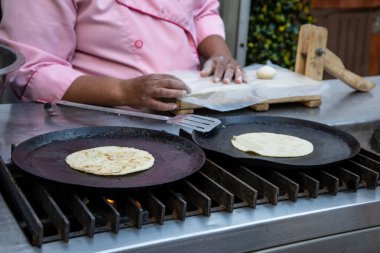 Comal 'ın üzerinde mısır tortillası yapan kadın ellerine yakın çekim. Geleneksel Meksika yemekleri.