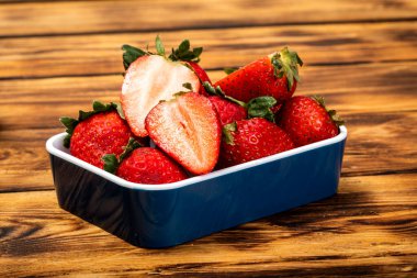 Kırsal ahşap masada taze ve bölünmüş çilekler. Renk dolu lezzetli meyveler..