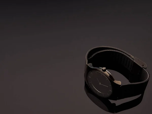 Black ladies luxury watch with metal strap mesh on a table gray gradient background