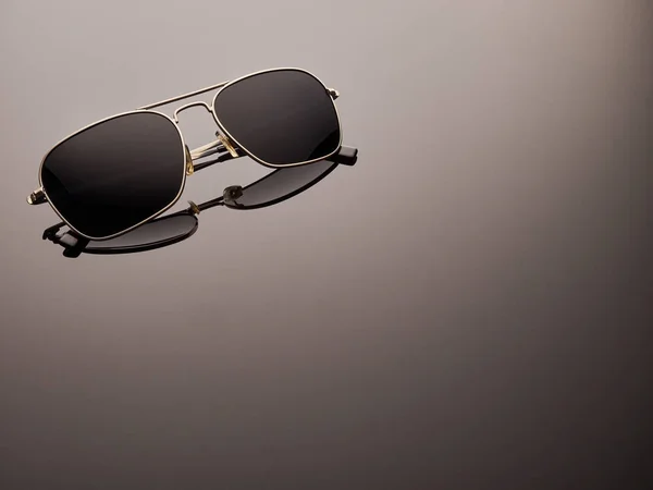 Şık yansıtılmış neredeyse yuvarlak metal çerçeve ve katlanmış kulak kolları ile güneş gözlüğü polarize. Logo kaldırıldı.