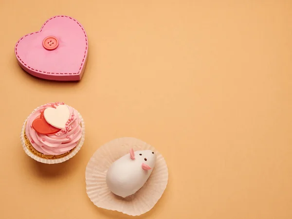 Düğmeli pembe kalp figürü ve kapkekleri olan bej arkaplanda da boşluk kopyala.