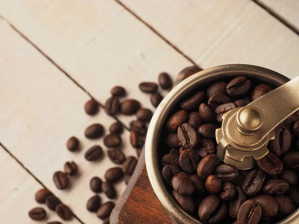 Koyu ve açık ahşap arka planda kahve tanecikleri olan yakın çekim kahve değirmeni..