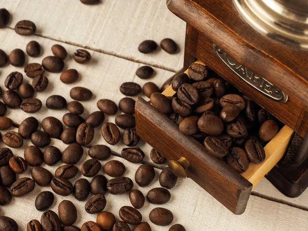 Koyu ve açık ahşap arka planda kahve tanecikleri olan yakın çekim kahve değirmeni..