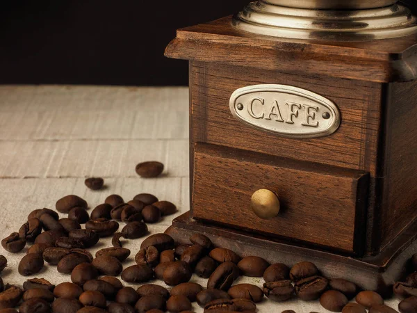 Koyu ve açık ahşap arka planda kahve tanecikleri olan yakın çekim kahve değirmeni..