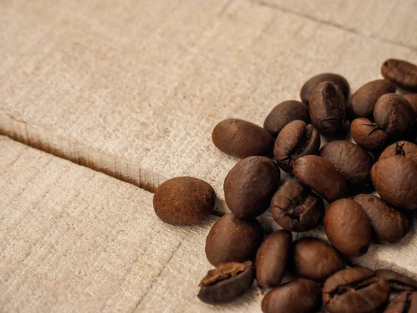 Koyu kahve taneleri açık ahşap masanın üzerinde duruyor, arka plan görüntüsü. metin için yer