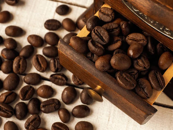 Koyu ve açık ahşap arka planda kahve tanecikleri olan yakın çekim kahve değirmeni..