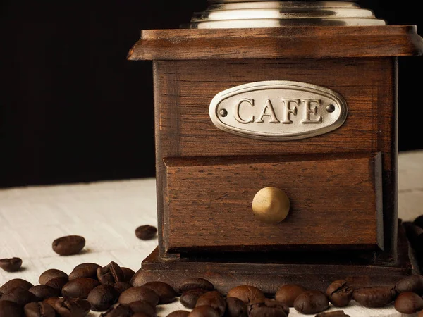 Koyu ve açık ahşap arka planda kahve tanecikleri olan yakın çekim kahve değirmeni..