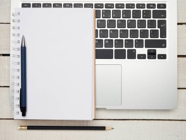 İş yeri - dizüstü bilgisayar, defter, kalem ve kalem beyaz ahşap bir masada uzaktan çalışma için. Ev ya da ofis için serbest bilgisayar. Kopyalama alanı olan arkaplan.