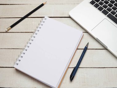 İş yeri - dizüstü bilgisayar, defter, kalem ve kalem beyaz ahşap bir masada uzaktan çalışma için. Ev ya da ofis için serbest bilgisayar. Kopyalama alanı olan arkaplan.