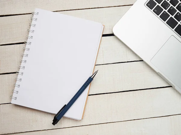 İş yeri - dizüstü bilgisayar, defter, kalem ve kalem beyaz ahşap bir masada uzaktan çalışma için. Ev ya da ofis için serbest bilgisayar. Kopyalama alanı olan arkaplan.