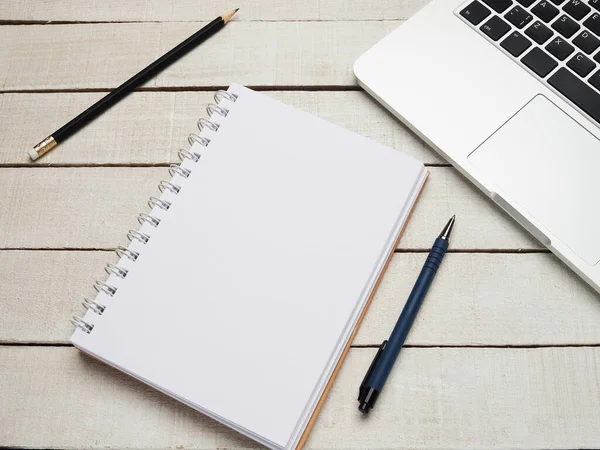 İş yeri - dizüstü bilgisayar, defter, kalem ve kalem beyaz ahşap bir masada uzaktan çalışma için. Ev ya da ofis için serbest bilgisayar. Kopyalama alanı olan arkaplan.