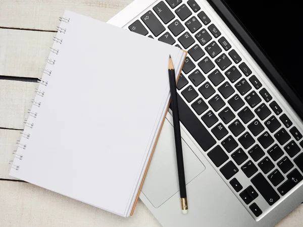 İş yeri - dizüstü bilgisayar, defter, kalem ve kalem beyaz ahşap bir masada uzaktan çalışma için. Ev ya da ofis için serbest bilgisayar. Kopyalama alanı olan arkaplan.