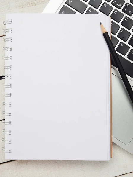 İş yeri - dizüstü bilgisayar, defter, kalem ve kalem beyaz ahşap bir masada uzaktan çalışma için. Ev ya da ofis için serbest bilgisayar. Kopyalama alanı olan arkaplan.