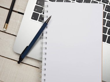 İş yeri - dizüstü bilgisayar, defter, kalem ve kalem beyaz ahşap bir masada uzaktan çalışma için. Ev ya da ofis için serbest bilgisayar. Kopyalama alanı olan arkaplan.