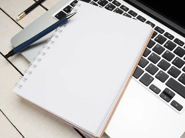 İş yeri - dizüstü bilgisayar, defter, kalem ve kalem beyaz ahşap bir masada uzaktan çalışma için. Ev ya da ofis için serbest bilgisayar. Kopyalama alanı olan arkaplan.