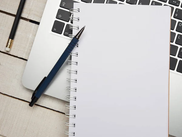İş yeri - dizüstü bilgisayar, defter, kalem ve kalem beyaz ahşap bir masada uzaktan çalışma için. Ev ya da ofis için serbest bilgisayar. Kopyalama alanı olan arkaplan.