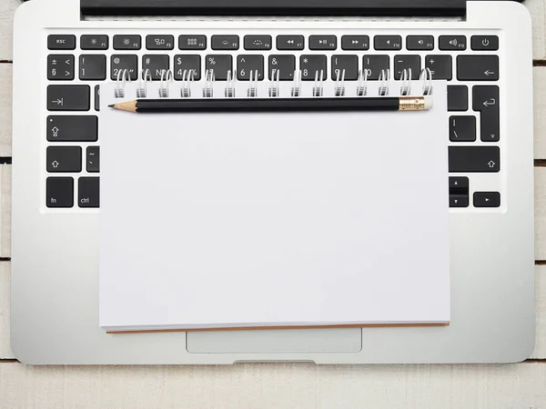 İşyeri - dizüstü bilgisayar, defter ve kalem beyaz ahşap bir masa üzerinde uzaktan çalışma için. Ev ya da ofis için serbest bilgisayar. Kopyalama alanı olan arkaplan.