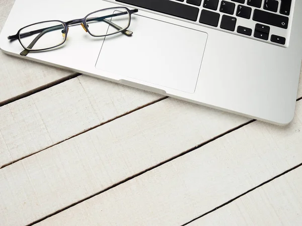 İşyeri - dizüstü bilgisayar ve uzaktan kumanda için gözlük beyaz ahşap bir masada. Ev ya da ofis için serbest bilgisayar. Kopyalama alanı olan arkaplan.