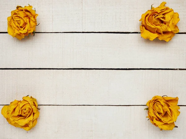 Beyaz ahşap arka planda kurumuş gül çiçekleri. Uzayı kopyala Çerçeve. Metin ve tasarım için yer. Tebrik kartı. Düz yerde, üst tarafta. Seçici odak.