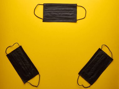 İzole edilmiş sarı arkaplan kopyalama boşluğunda üç siyah tıbbi maske