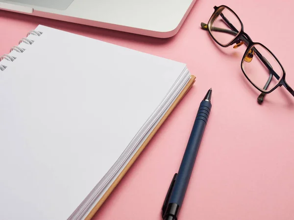 Düz, üst görünüm ofis masası çerçevesi. Laptop, gözlük, pembe arka planda not defteri. Ev Uzaktan Çalışma Eğitimi Coronavirus Quantin.