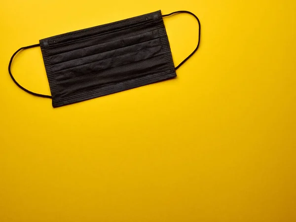İzole edilmiş sarı arkaplan kopyalama alanı üzerinde siyah tıbbi maske