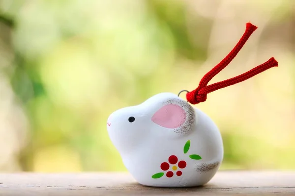 A cute looking Japanese good luck charm rat for celebrating year of the rat on green background.