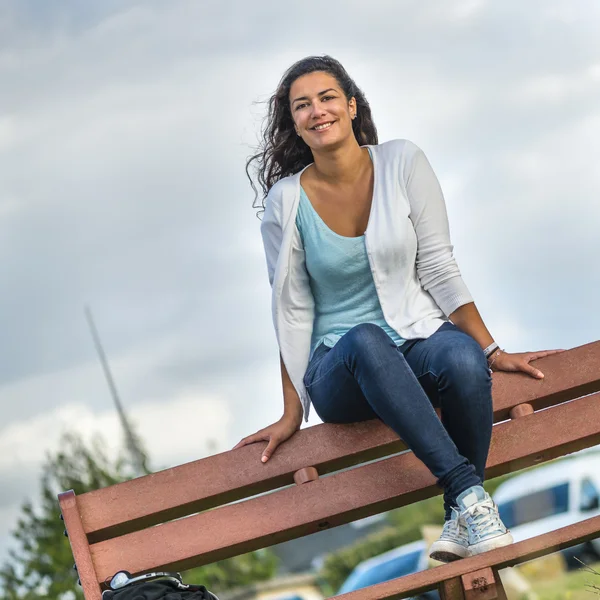 Mooie jonge vrouw zit op bankje met kopie ruimte — Stockfoto