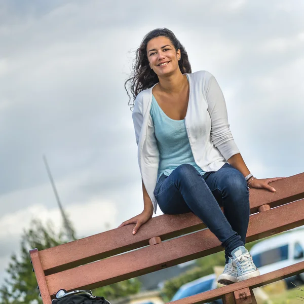 Красивая молодая женщина сидит на скамейке с копировальным пространством Лицензионные Стоковые Изображения