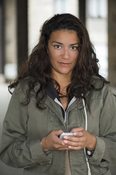 Young woman into hall holding her smartphone and thinking