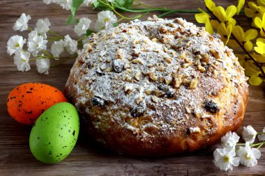 Paskalya yumurtaları ve çiçeklerle örülmüş ev yapımı Paskalya ekmeği - ahşap masanın üzerinde - Paskalya zamanı