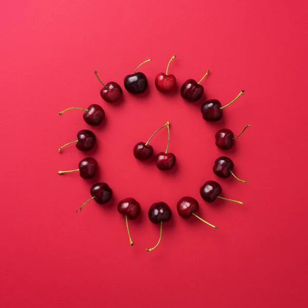 Třešně, které jsou uspořádány na červeném pozadí — Stock fotografie
