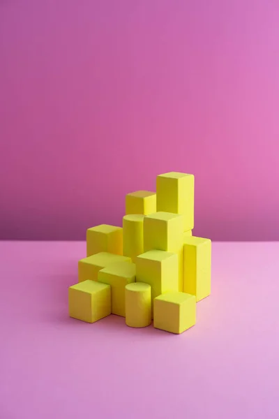 Cubos de bloque amarillo organizados sobre fondo rosa — Foto de Stock