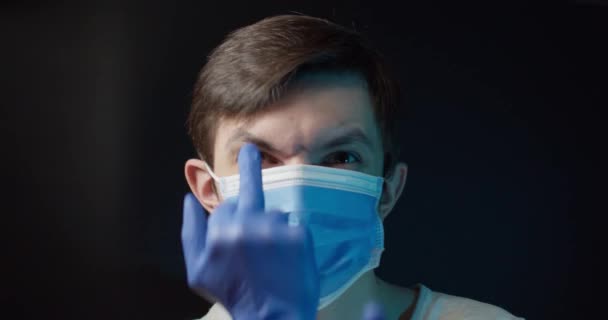 Un uomo con una maschera medica mostra cattivi gesti — Video Stock