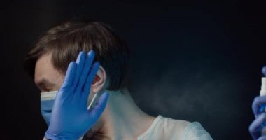 Tıbbi maskeli bir adam üzerine antiseptik fışkırtır ama bunu istemez.