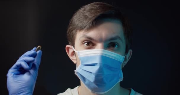 Un hombre con una máscara médica come una pastilla del virus — Vídeos de Stock