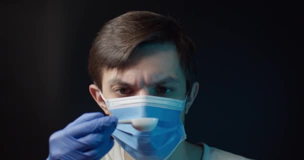 Человек в медицинской маске съедает медицинский порошок и выплевывает его — стоковое видео