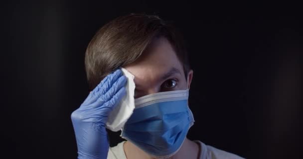Ένας άντρας με ιατρική μάσκα στεγνώνει το μέτωπό του με μια πετσέτα. — Αρχείο Βίντεο