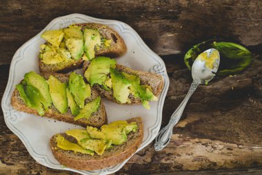 Tahta bir masada nefis avokado sandviçi.
