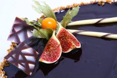 Lezzetli bir tatlı. Meyvelerle süslenmiş peynirli kek üzerine sos dökülmüş..