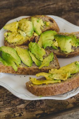 Tahta bir masada nefis avokado sandviçi.