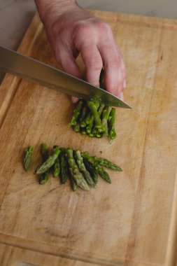 Yemek, doğal. Adam kuşkonmaz kesiyor.