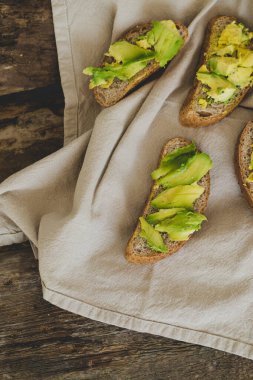 Tahta bir masada nefis avokado sandviçi.