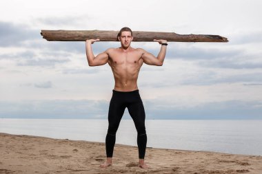 Spor, spor. Sahilde büyük bir odunu olan vücut geliştirici.