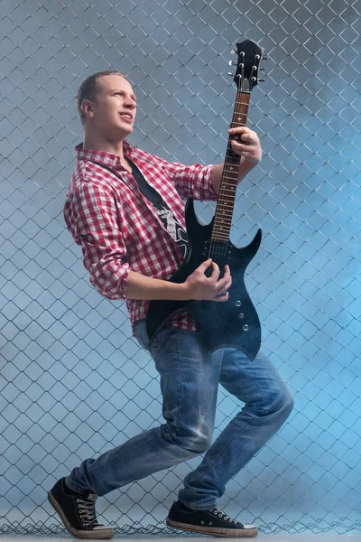 フェンスの背景にギターを持つ音楽家 — ストック写真