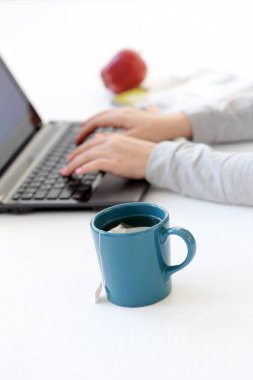 Dizüstü bilgisayarı ve bir fincan çayı olan bir kız.