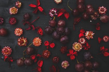 Masanın üzerinde kırmızı üzümler ve kurumuş çiçekler var.