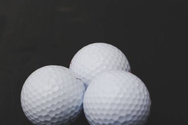 Siyah arka planda birkaç golf topu var.
