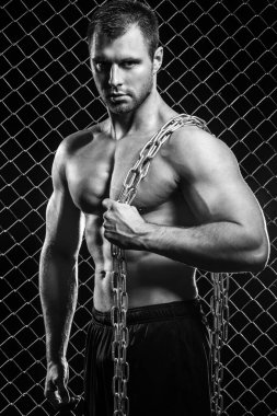 Güzel, güçlü, çitlerin arkasında zinciri olan bir adam.