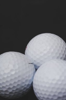 Siyah arka planda birkaç golf topu var.